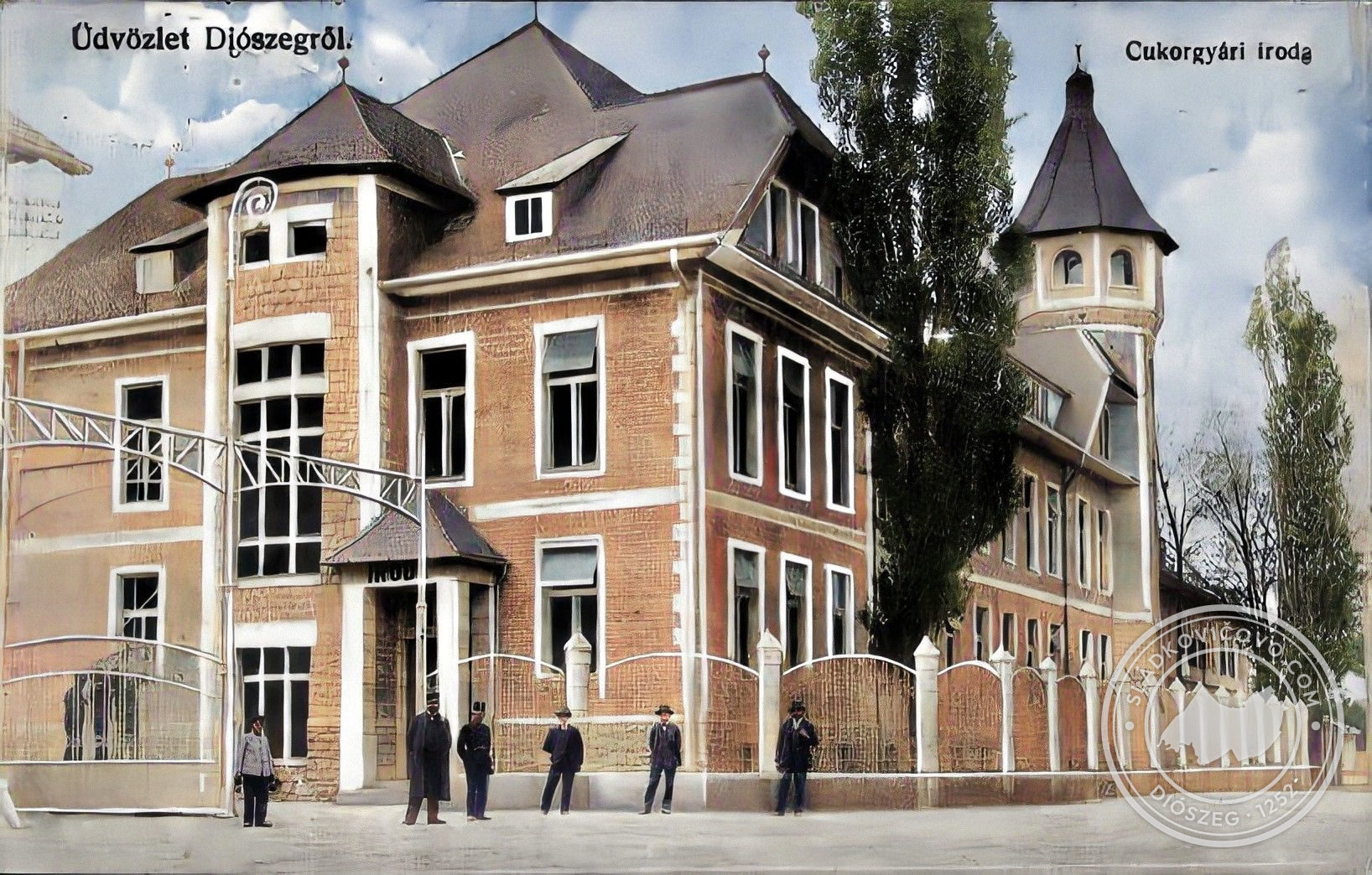 A cca. 1914-16 körül készült színezett fényképen a cukorgyár adminisztratív épülete, az igazgatóság látható, a háttérben a kaszinó épülete.