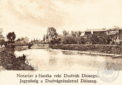 A Dudvág a híddal és a Községháza, ma Városi Hivatal épületének hátsó szárnya a múlt század húszas éveiben.