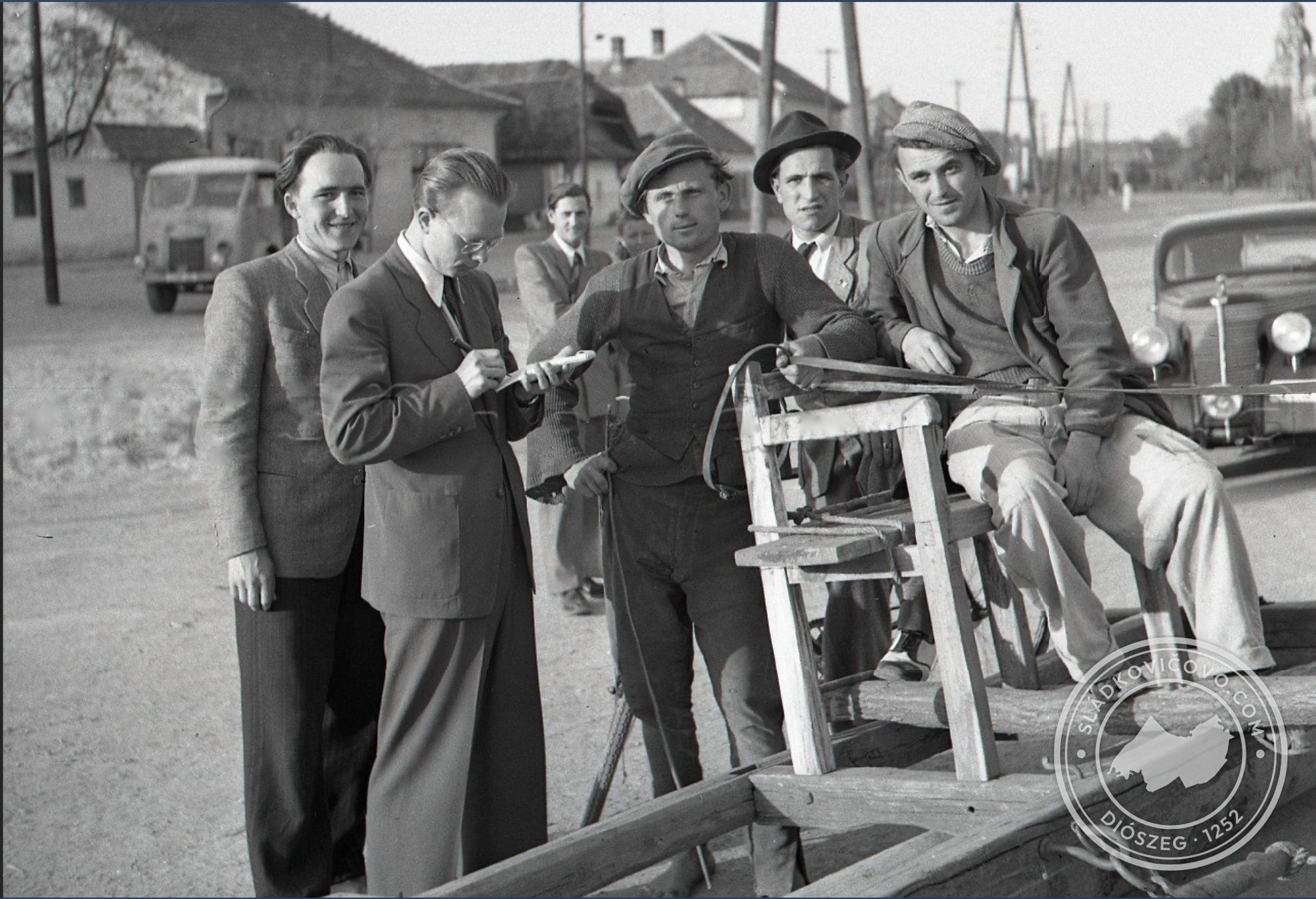 1947-ben a főtéren készült fénykép. Napos tavaszi időben a főtér felületét lópár húzta hengerrel egyengették. A háttérben még az eredeti beépítés látható.